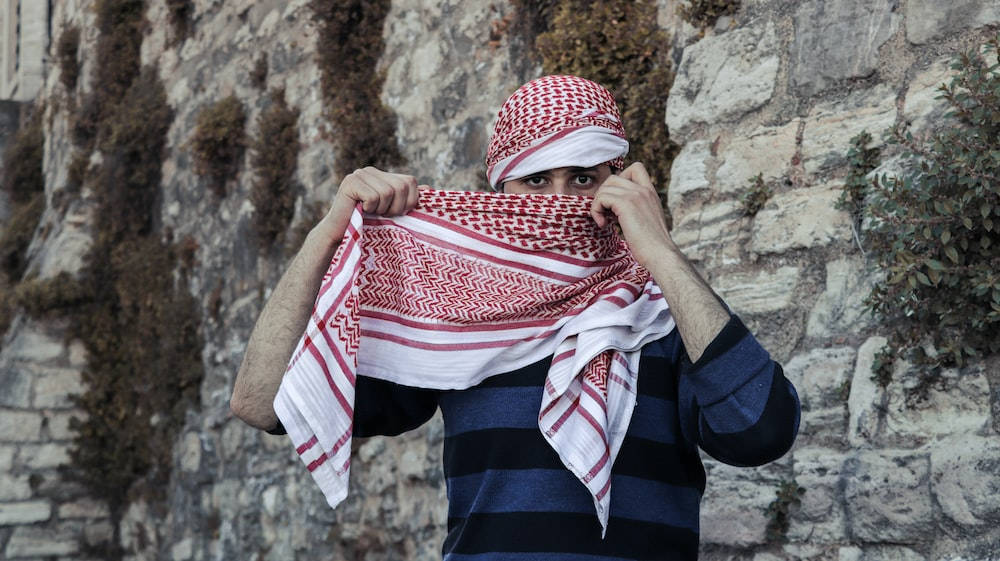 Băiat islamic cu eșarfă roșie în carouri Fundal