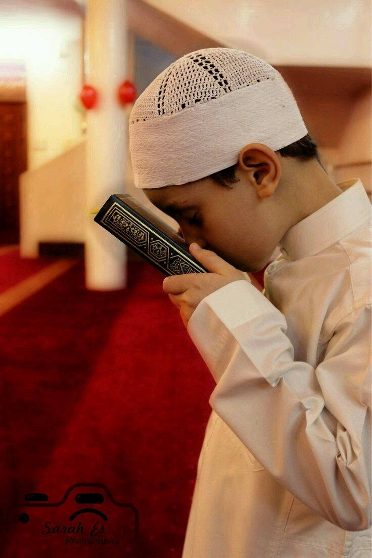 Băiat islamic sărutând Coranul Fundal