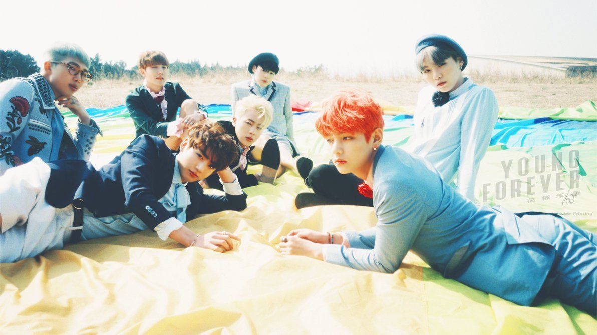 Membrii BTS întinși pe un prosop pe nisipul plajei în timpul verii. — Bts Fundal