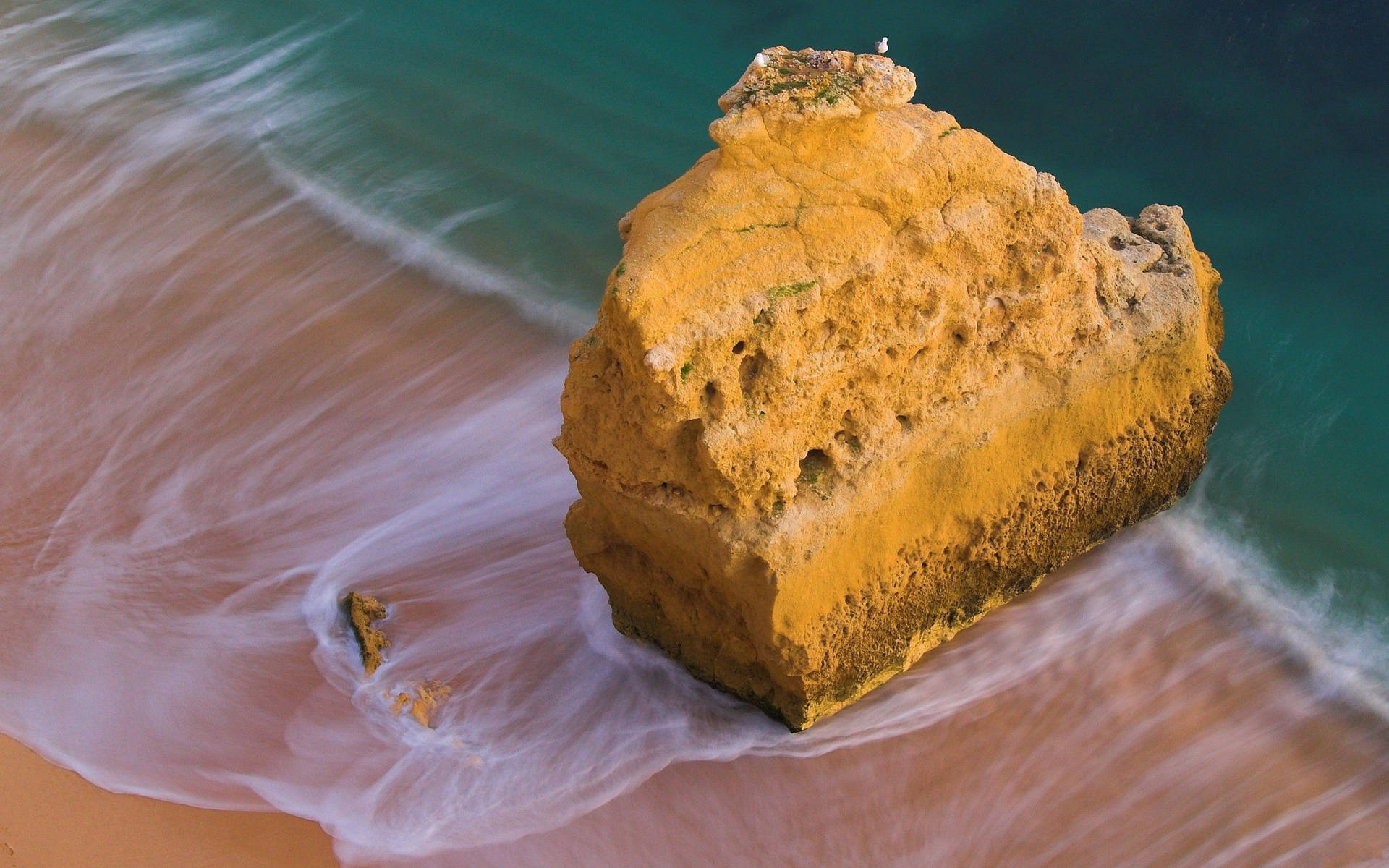 Ocean cu o stâncă mare galbenă pe țărm sau nisip și valuri albe. — Ocean Fundal