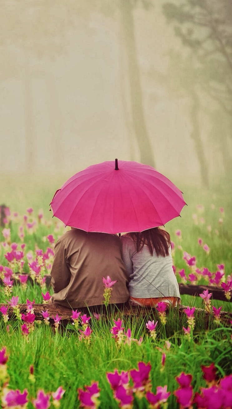 Cuplu drăguț cu umbrelă în grădină cu flori Fundal