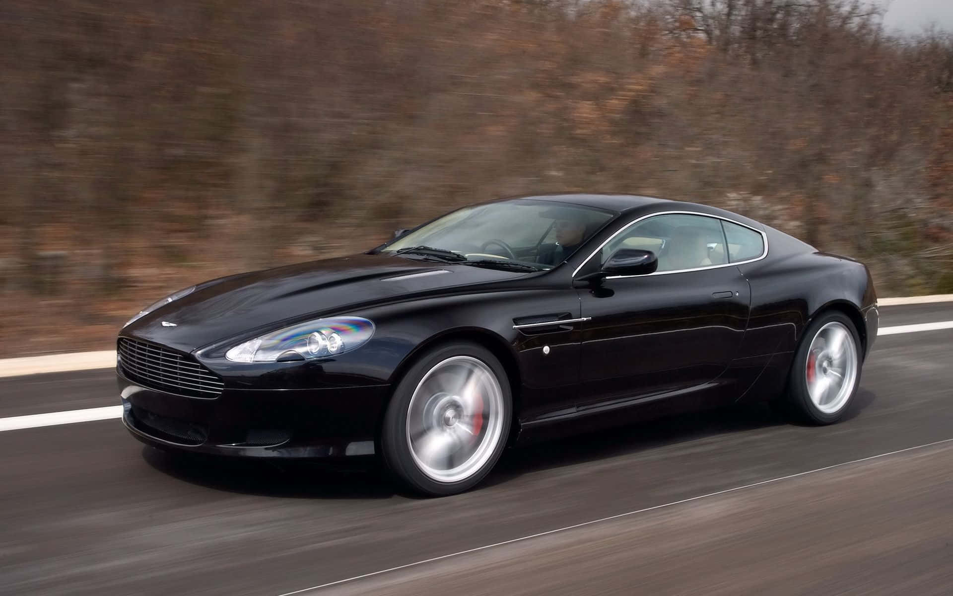 Elegantul Aston Martin DB9 pe un drum deschis Fundal