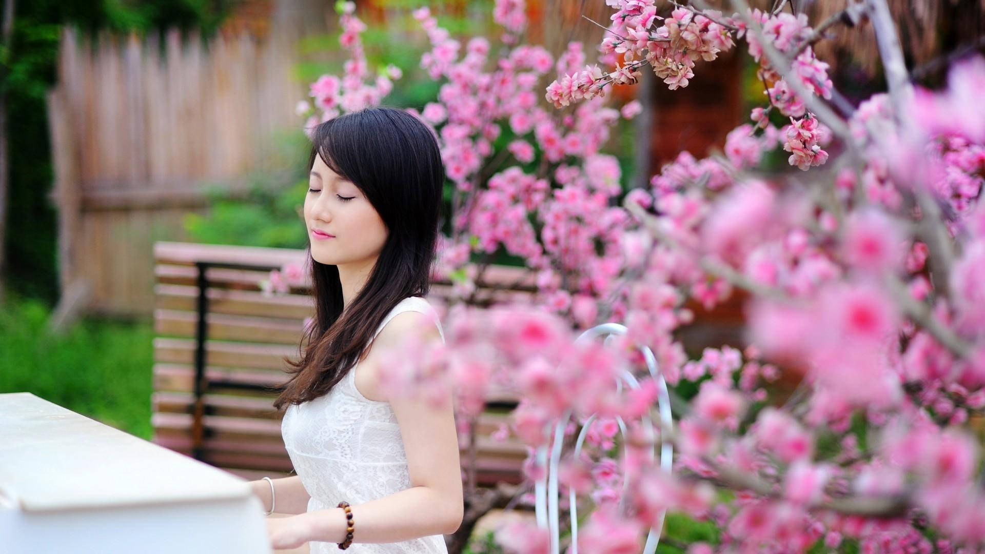 Fata japoneză cântând la pian în grădină cu flori roz Fundal