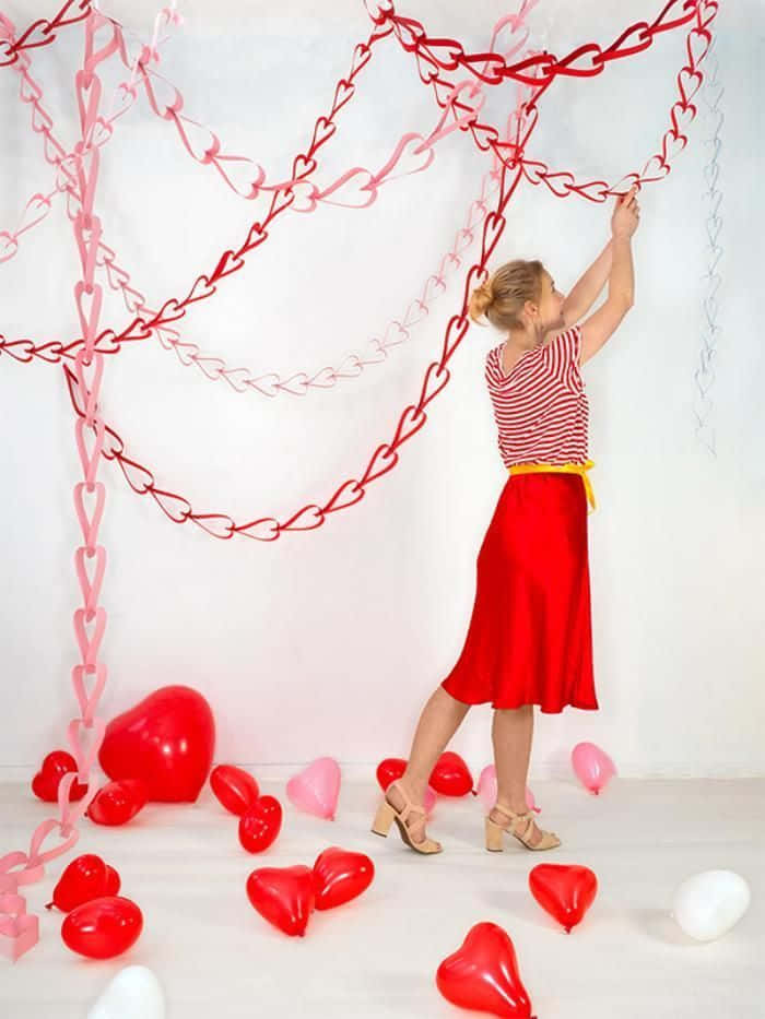Femeie cu lanturi de hartie in forma de inima pentru Valentine's Day Fundal
