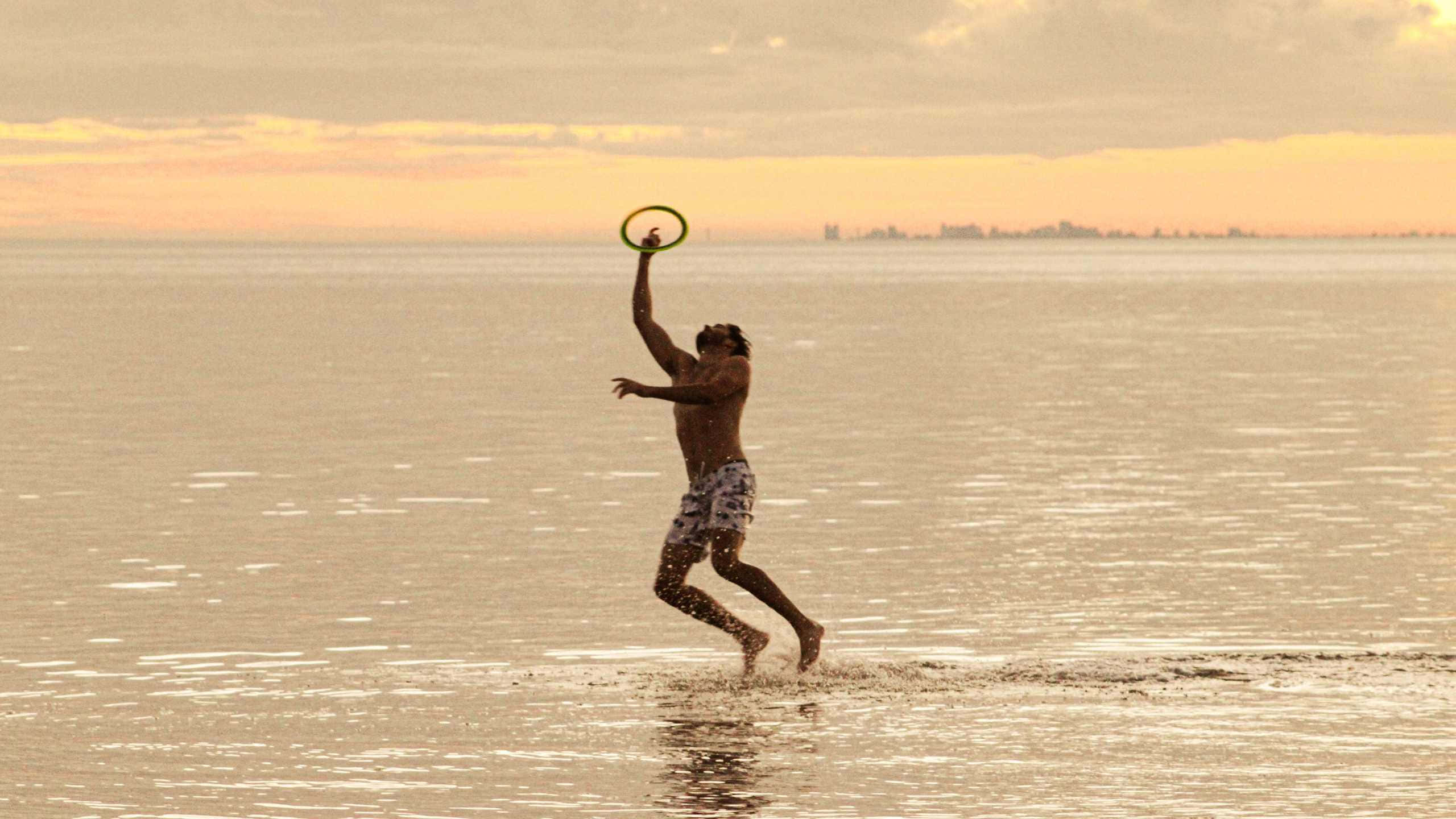 Fundal Sportiv 1440p cu Frisbee pe Plajă Fundal