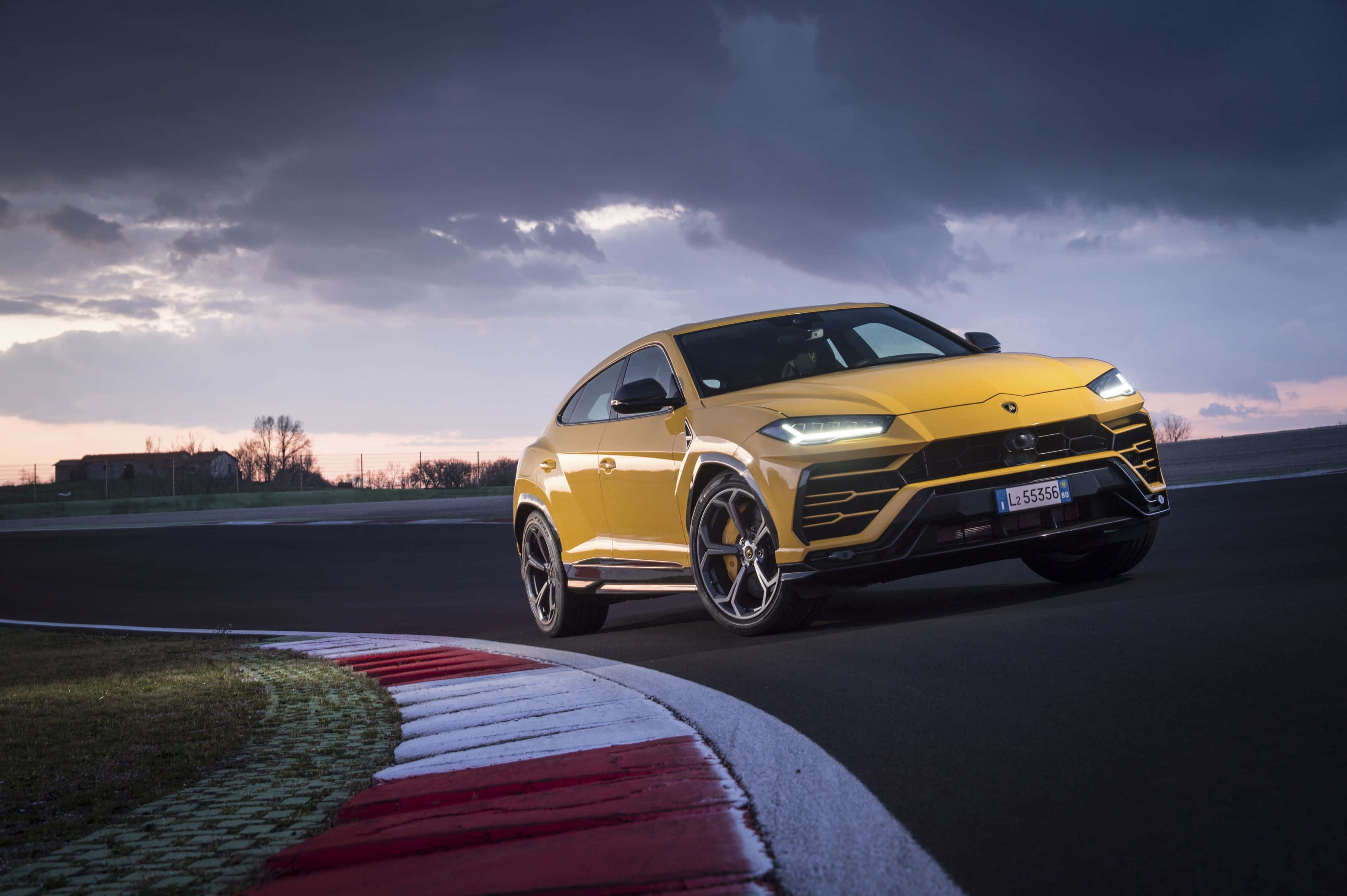lamborghini urus - un SUV galben care conduce pe un circuit Fundal