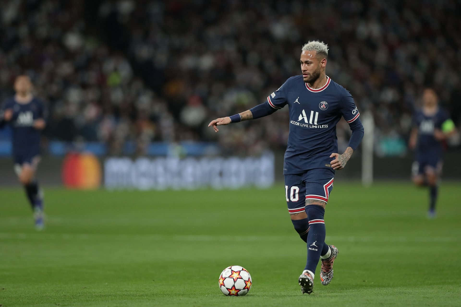 Neymar driblând mingea pe lângă un adversar. Fundal
