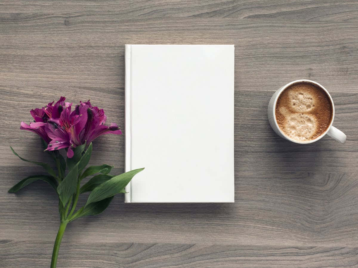 o carte albă și o ceașcă de cafea pe o masă de lemn Fundal