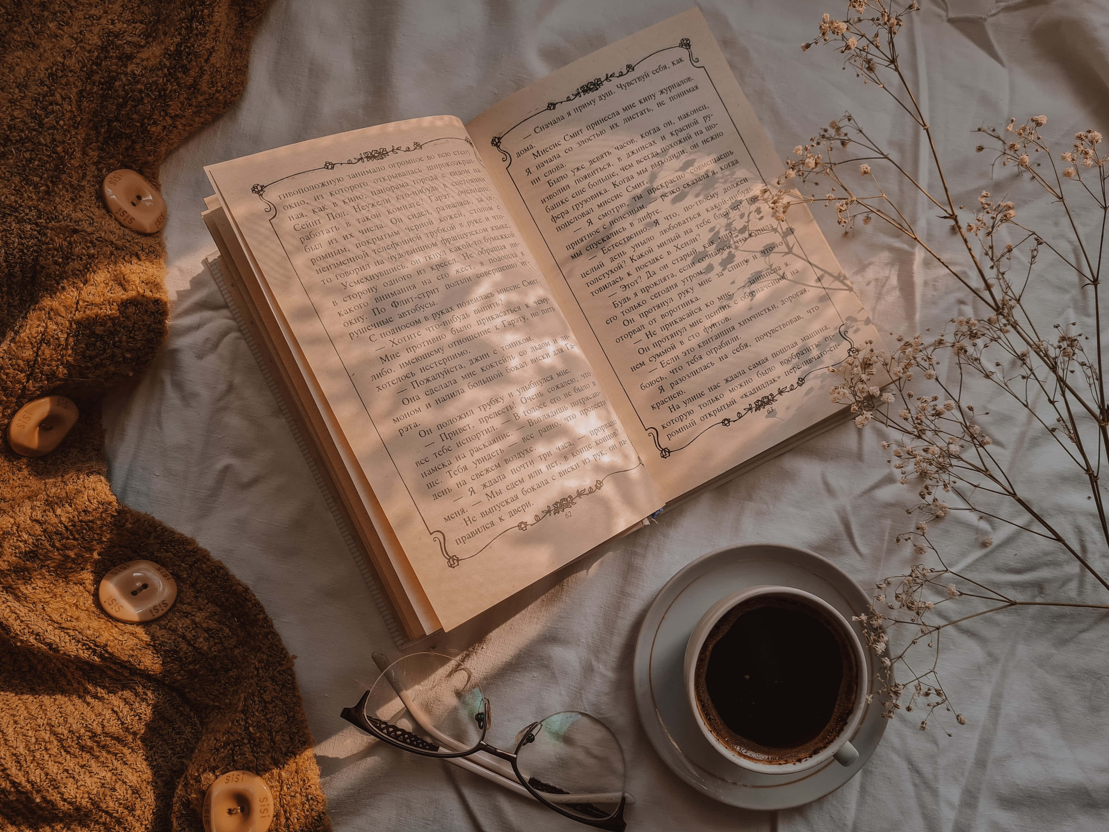 o carte, ochelari și cafea pe un pat Fundal