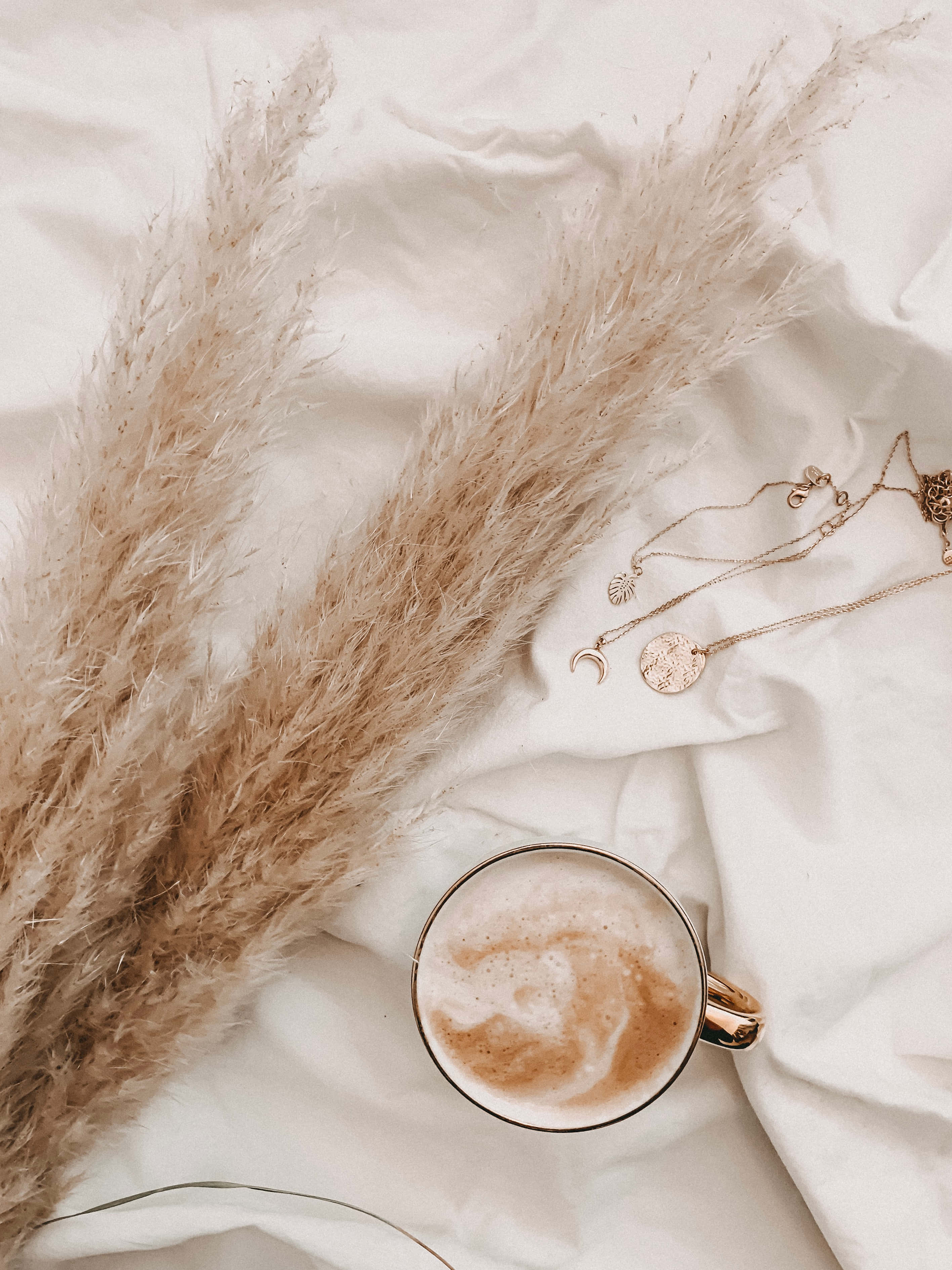 o ceașcă de cafea și un colier pe un pat Fundal