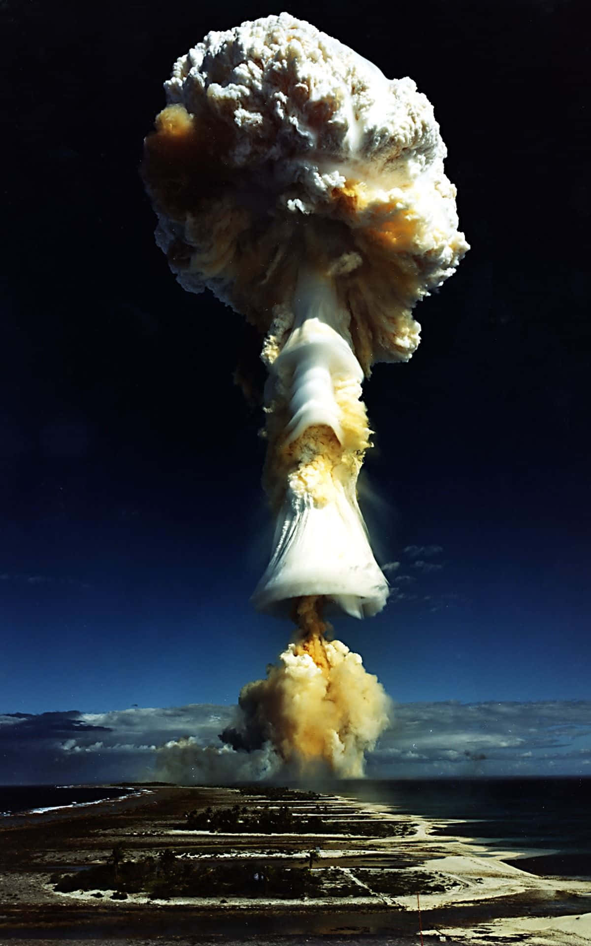 o explozie nucleară se vede deasupra unei plaje Fundal
