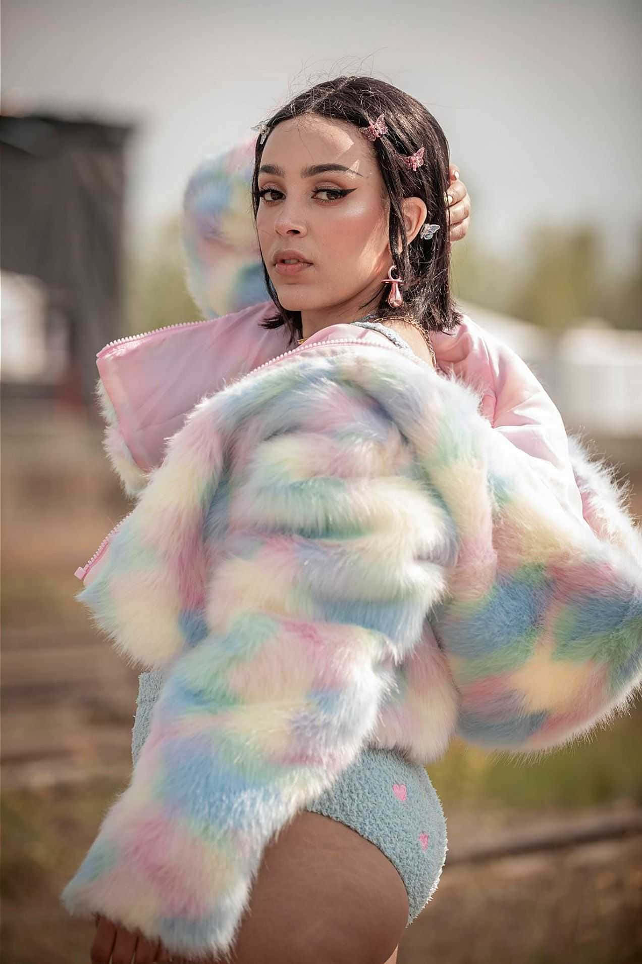o femeie într-o haină de blană colorată pozând Fundal