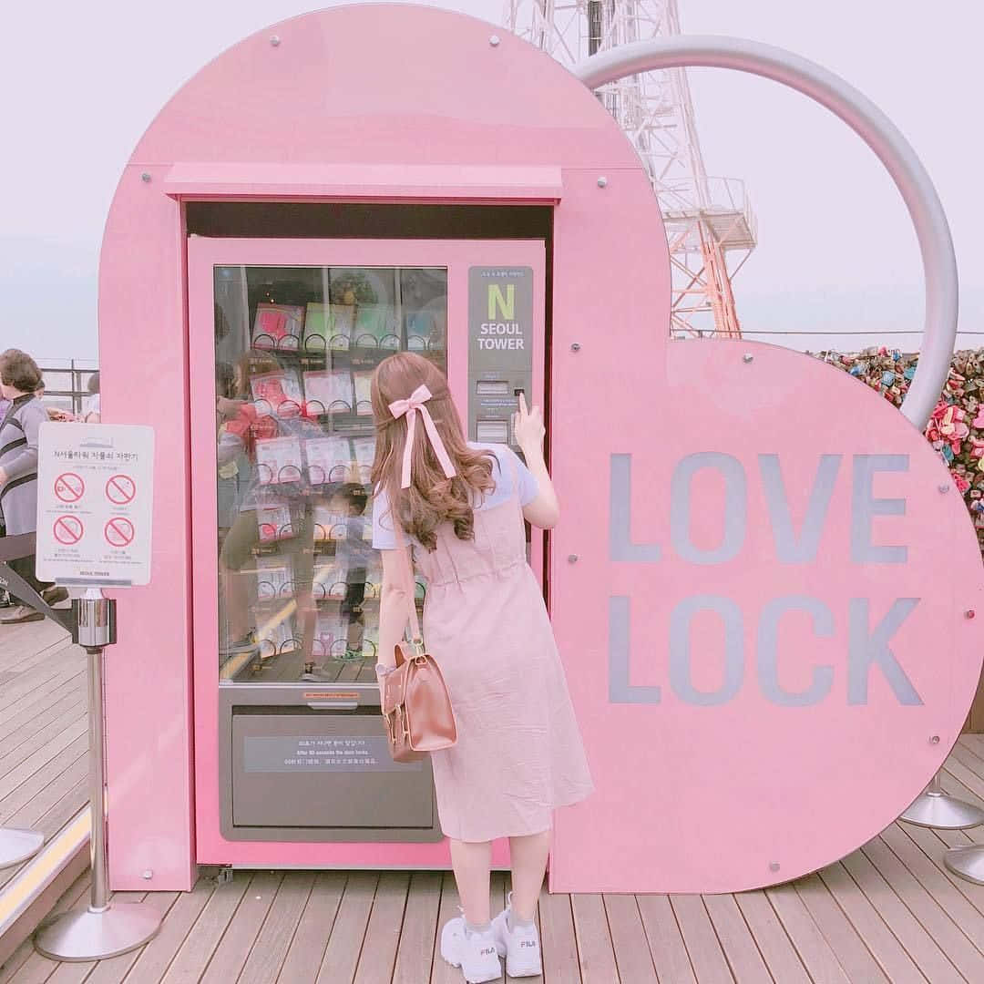 o femeie stând în fața unei mașini de vending roz Fundal