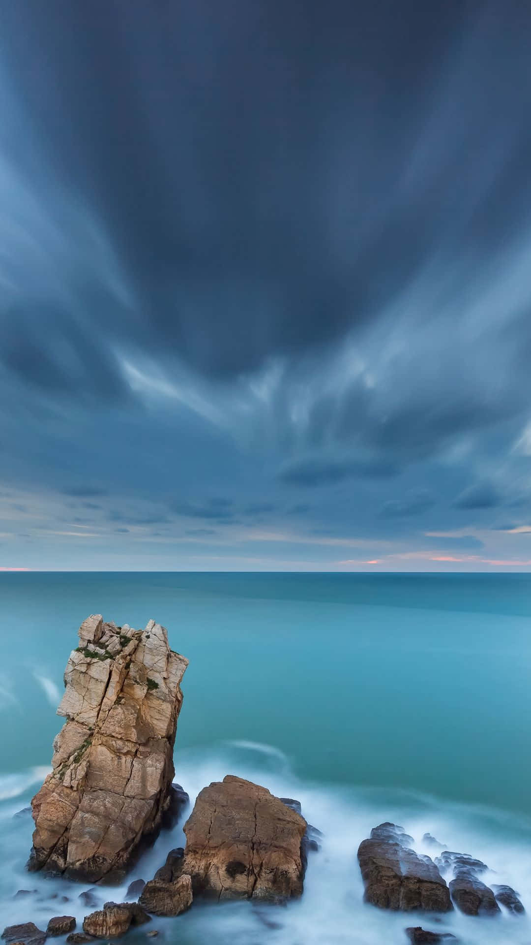 o formațiune stâncoasă cu cer întunecat și ocean Fundal