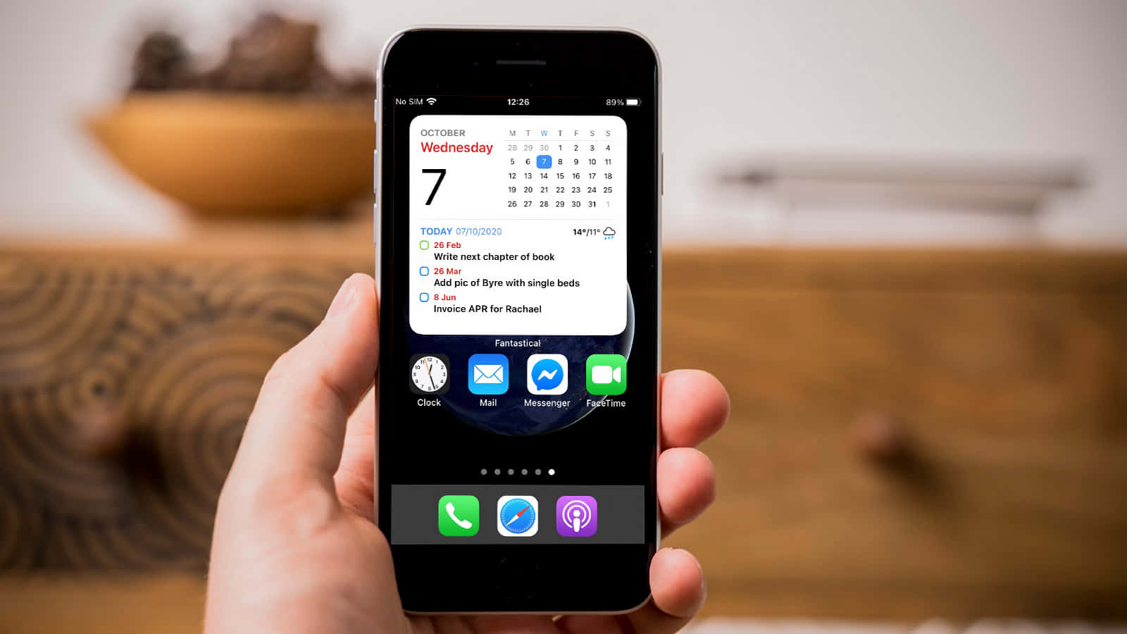 o persoană care ține un iPhone cu un calendar pe ecran Fundal