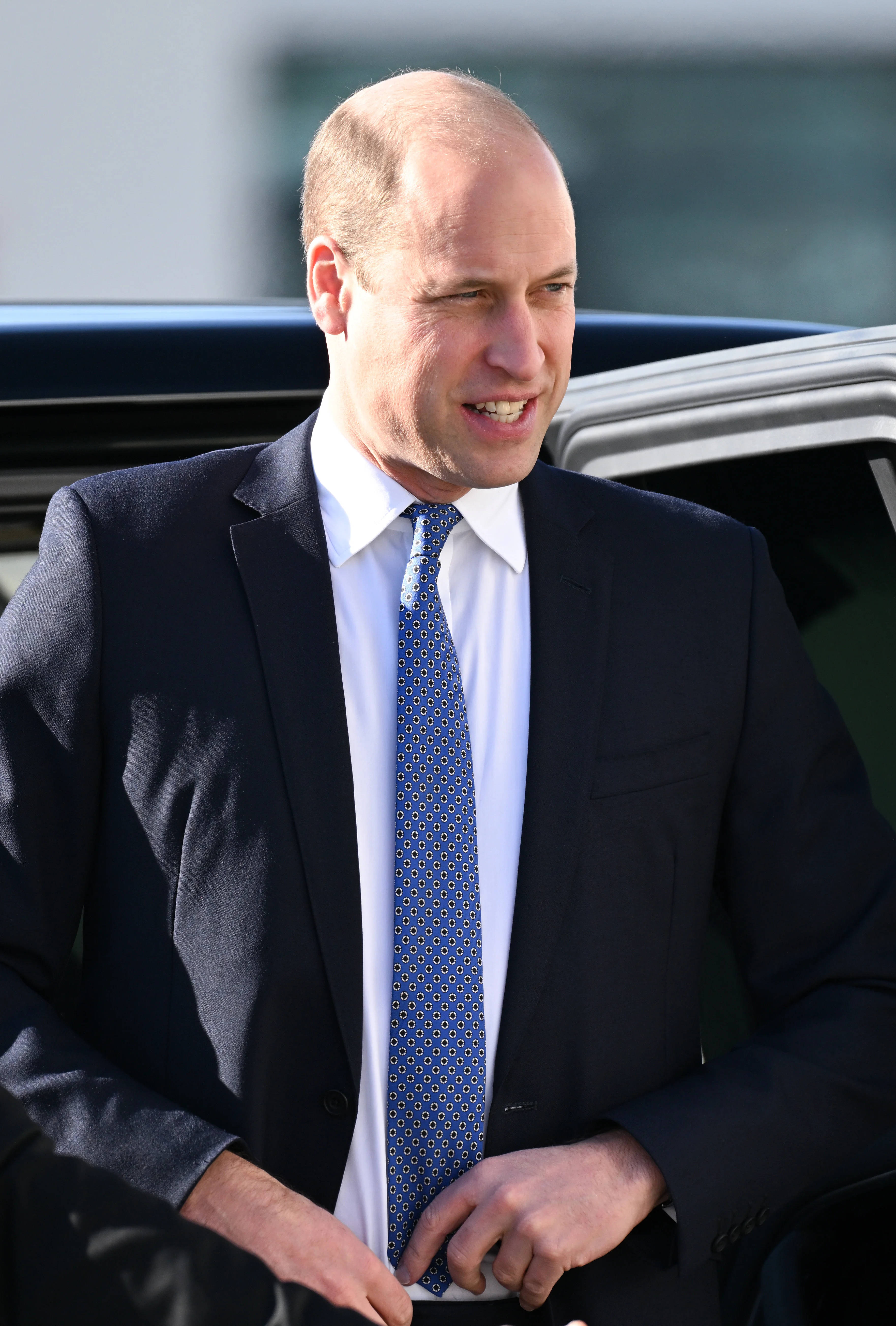 Prince William ajustându-și cravata de costum Fundal