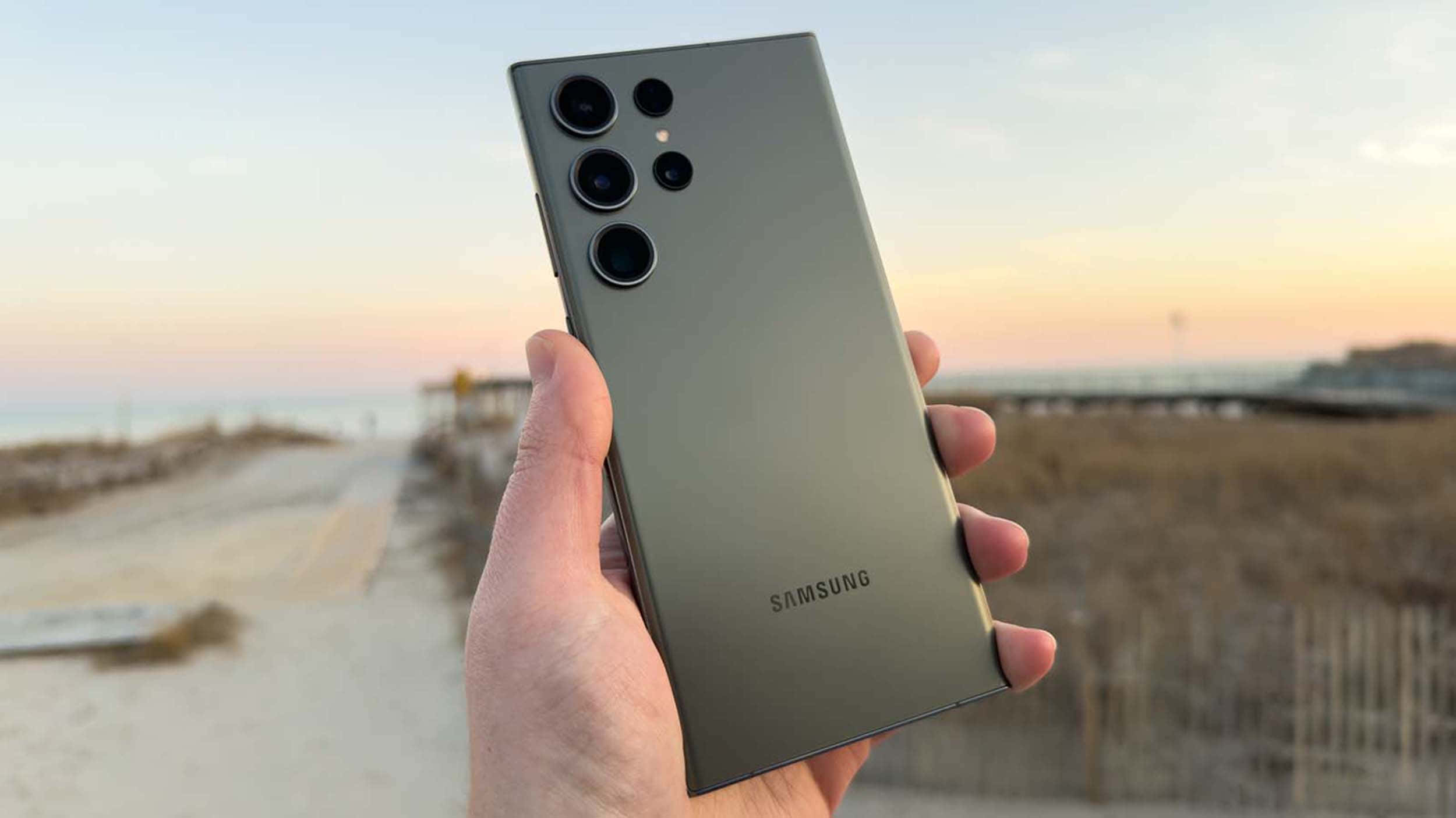 Samsung S23 Ultra ținut în mână pe fundal de plajă Fundal