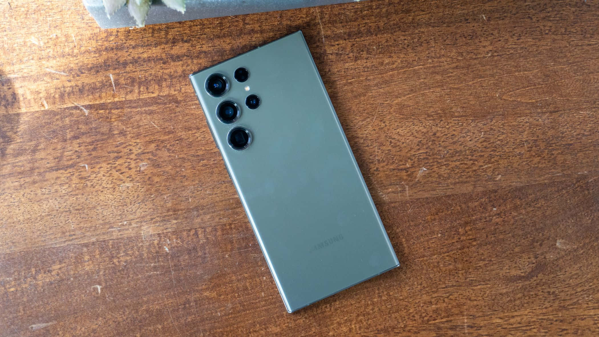 Samsung S23 Ultra verde spate cu ansamblu cameră pe suprafață din lemn Fundal