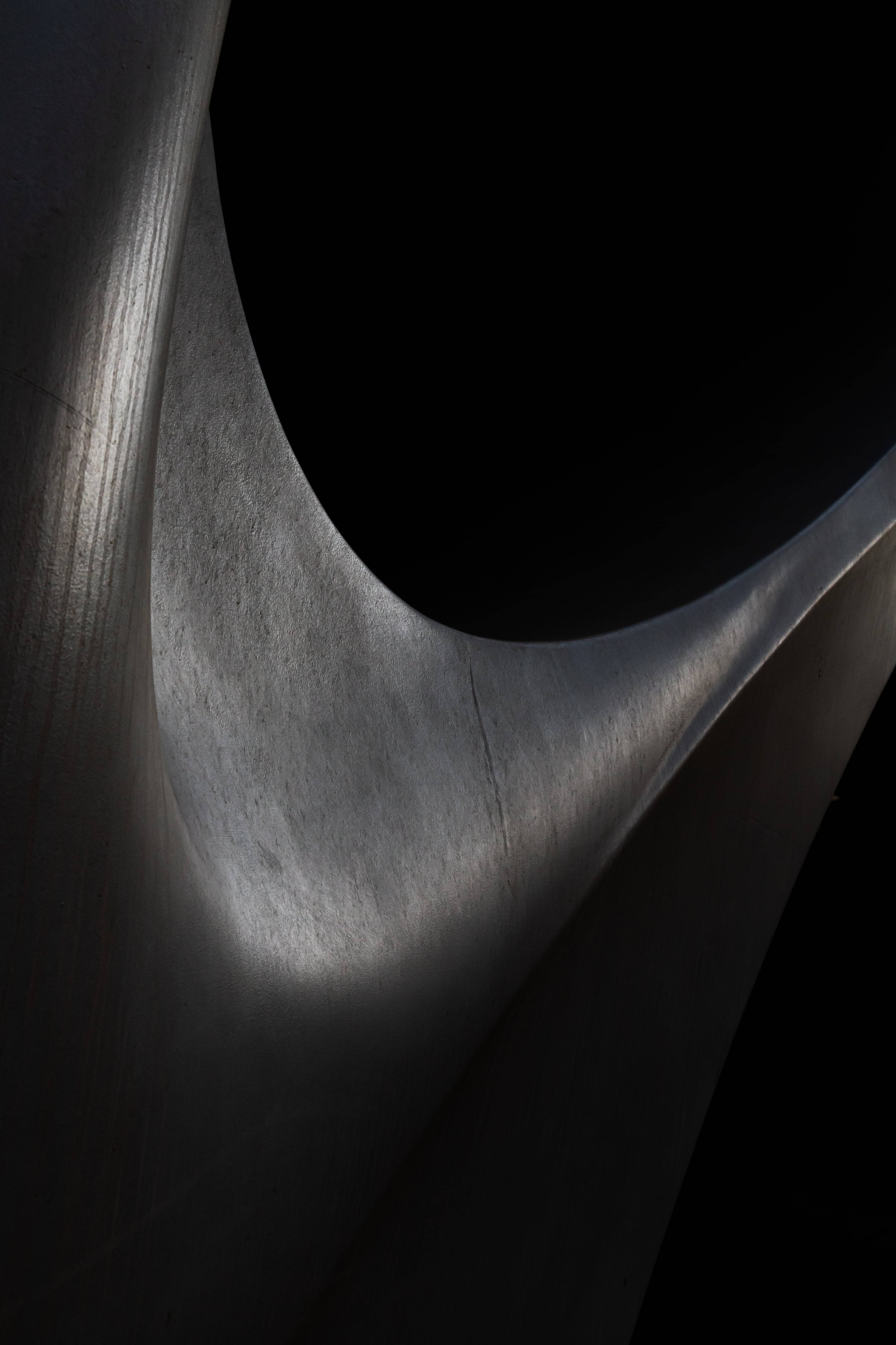 Sculptură abstractă neagră într-o cameră slab iluminată Fundal