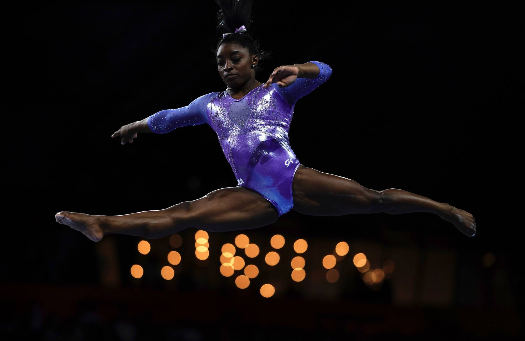Simon Biles în despăritura în aer Fundal