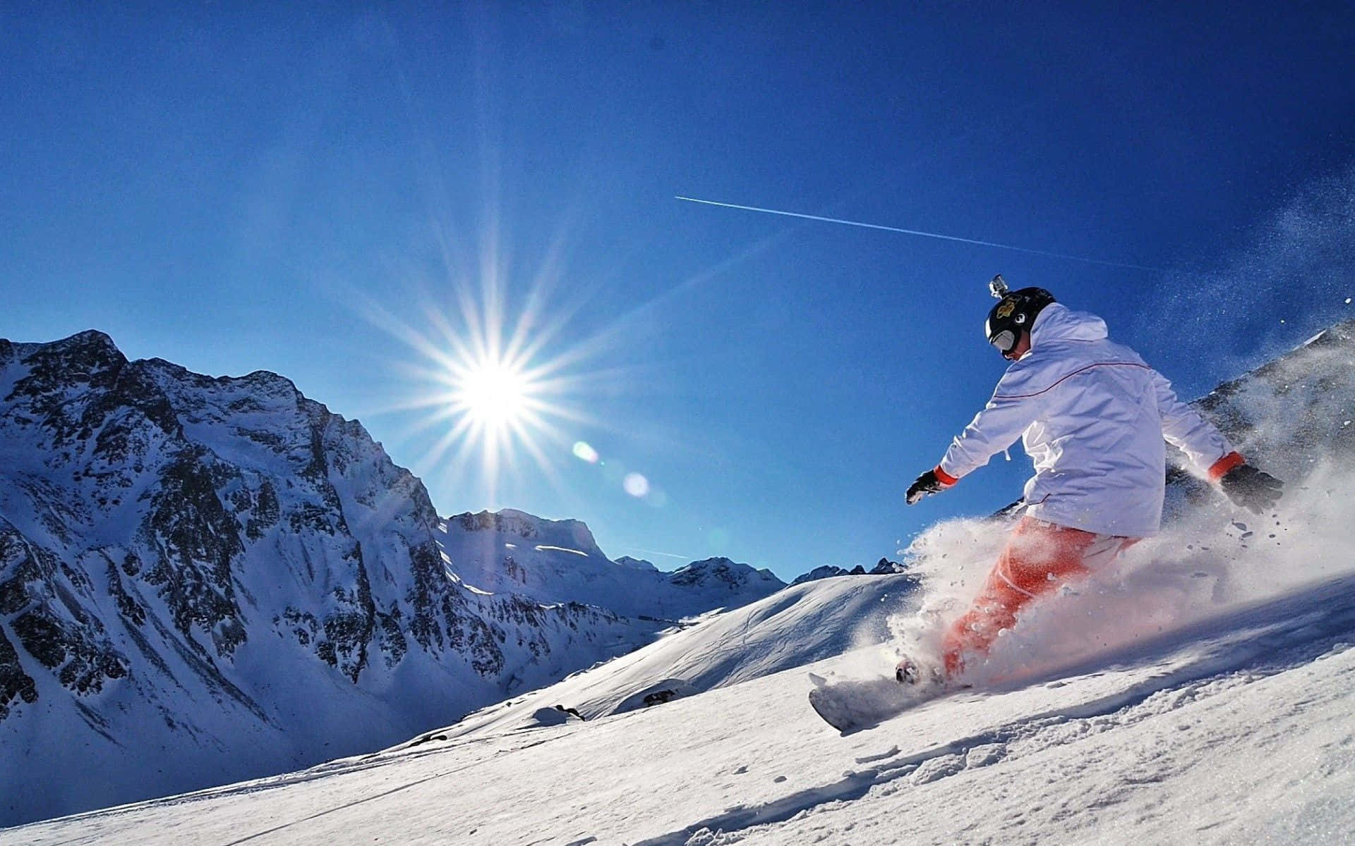 Snowboarder zboară deasupra unui munte înzăpezit Fundal