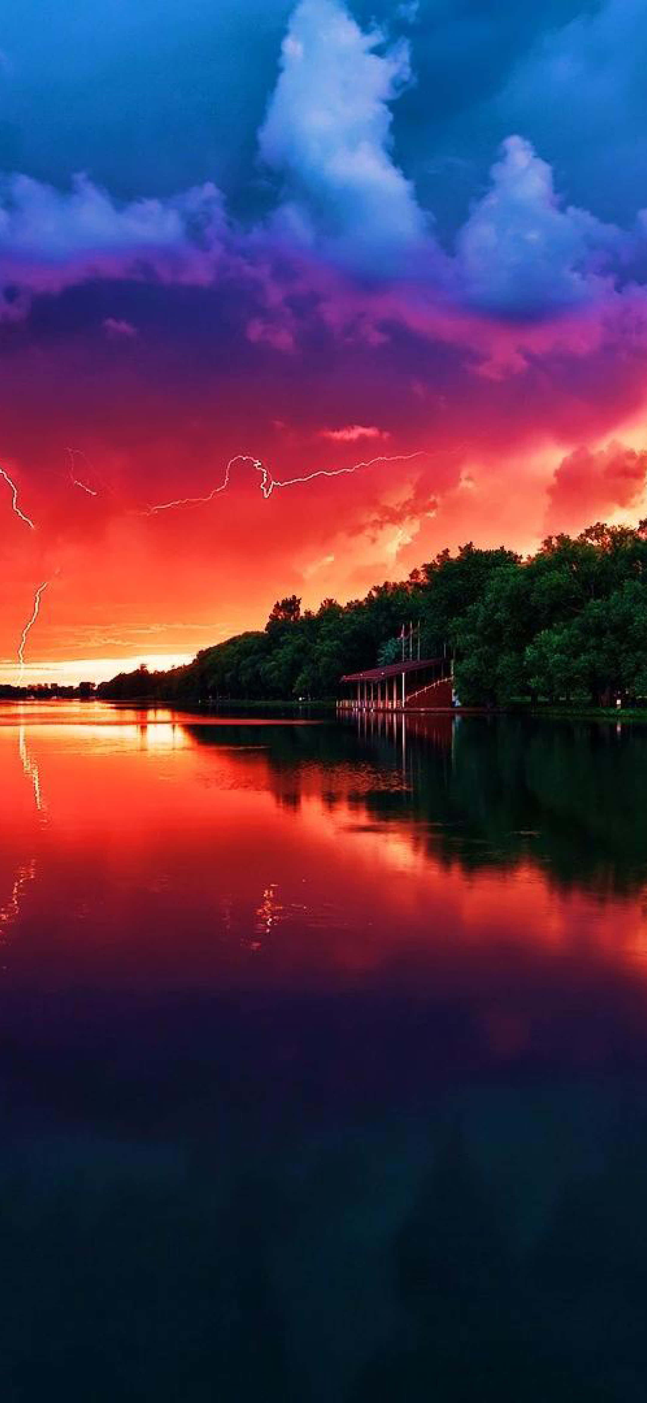 un apus de soare colorat deasupra unui lac, cu fulgere Fundal