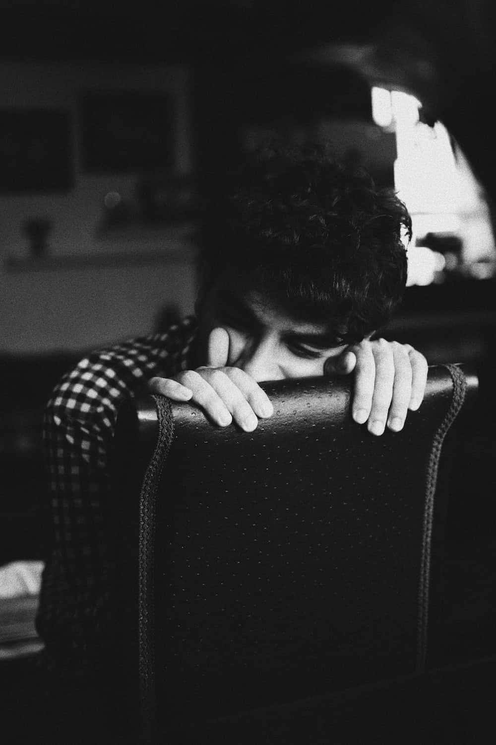 un bărbat stă pe un scaun cu mâna pe față Fundal