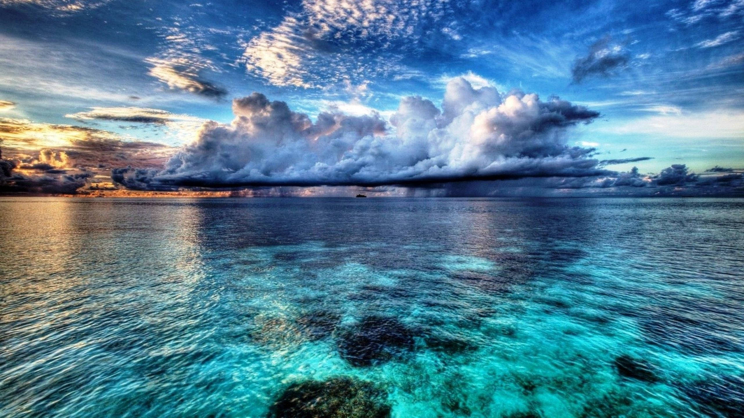 Un ocean albastru vast și majestuos, cu nori măreței cu nuanțe portocalii în cer. Fundal
