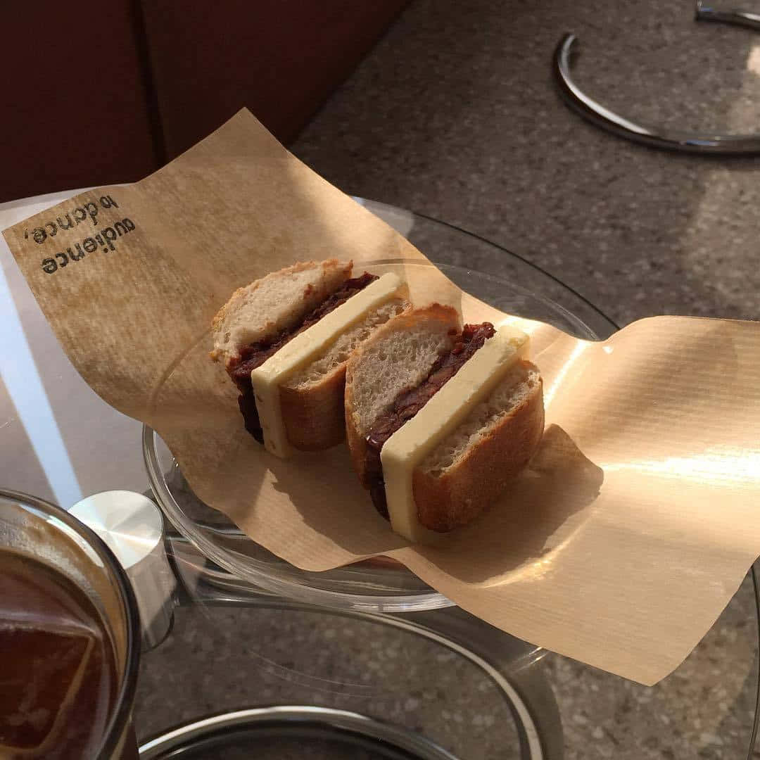 un sandviș pe o farfurie cu o ceașcă de cafea Fundal