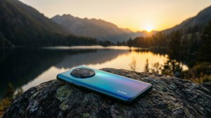 Telefon Huawei pe o stâncă, cu vedere spre un lac de munte la apus, peisaj senin. — Huawei Fundal