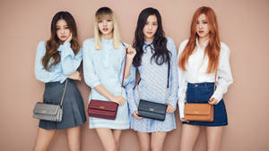 Fundal Blackpink cu membrele pozând cu genți tip sling pe un perete bej