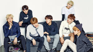 Membrii trupei BTS pozând pe canapea.