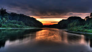 River calm în junglă sub cerul apusului de soare portocaliu wallpaper