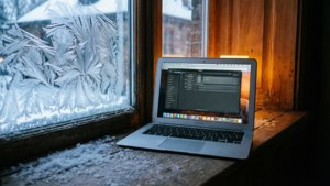 Un MacBook Air pe un pervaz înzăpezit, cu iluminare interioară confortabilă. — MacBook Fundal