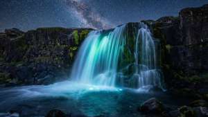 Cascada luminescentă sub un cer nocturn înstelat, cu negru profund. — De două ori Fundal