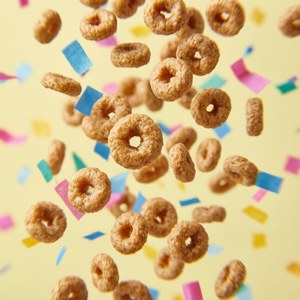 Wallpaper jucăus cu Cheerios căzând ca confetti pe un fundal galben pastel. — Tecno Phantom Fundal