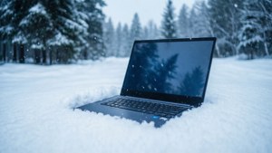 Un Chromebook așezat în zăpadă, cu un fundal de pădure înzăpezită.
