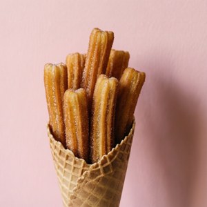 Churros stivuite într-un con, pe un fundal roz. — Huawei nova Flip S Fundal