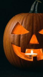 Prim-plan al unei sculpturi de dovleac iluminată, cu fundal întunecat — Atmosferă de Halloween Fundal