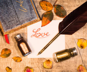 Inscripție portocalie „Love” scrisă pe o bucată de hârtie albă cu pană și sticle de cerneală pe o masă de lemn. Scrisoare de dragoste pentru Ziua Îndrăgostiților.