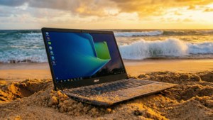 Un Chromebook așezat pe o plajă nisipoasă în timpul unui apus spectaculos.