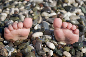 Picioare pe stânci în timpul vacanței de vară, situație amuzantă pe plaja cu pietricele.