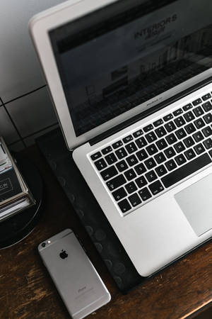 iPhone pe birou cu MacBook argintiu — Xiaomi Pad 7 Ultra Fundal