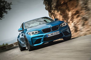 Tapet cu BMW M2 F87 albastru pe drum lângă munte