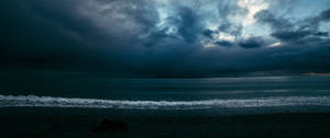 Cer ultrawide întunecat, cu puțină lumină reflectată pe ocean. — 2560x1080 Fundal