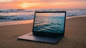 Un MacBook liniștit pe o plajă în timpul răsăritului, cu tonuri oceanice.
