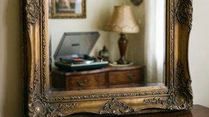 O oglindă vintage ornamentată care reflectă un interior retro confortabil.