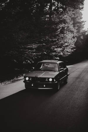 Tapet alb-negru cu o mașină BMW veche pe drum