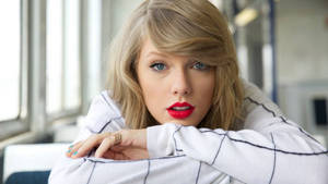 Taylor Swift cu bărbia sprijinită pe masă fotografie fundal.