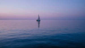 Un veleiro solitariu pe apele calme ale oceanului la amurg. — Ocean Fundal